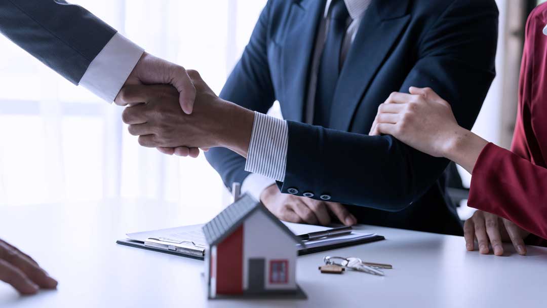 Happy couple first time home handshaking realtor